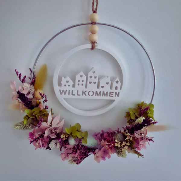Blumekranz, halb bedeckt mit Trockenblumen und einem Willkommen Ornament